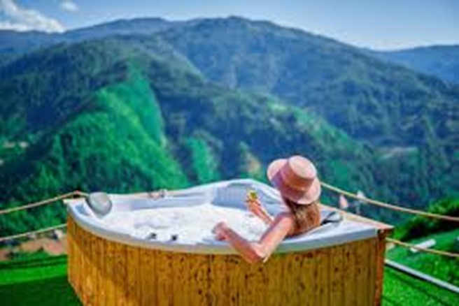 A person in a hot tub overlooking a valley  Description automatically generated